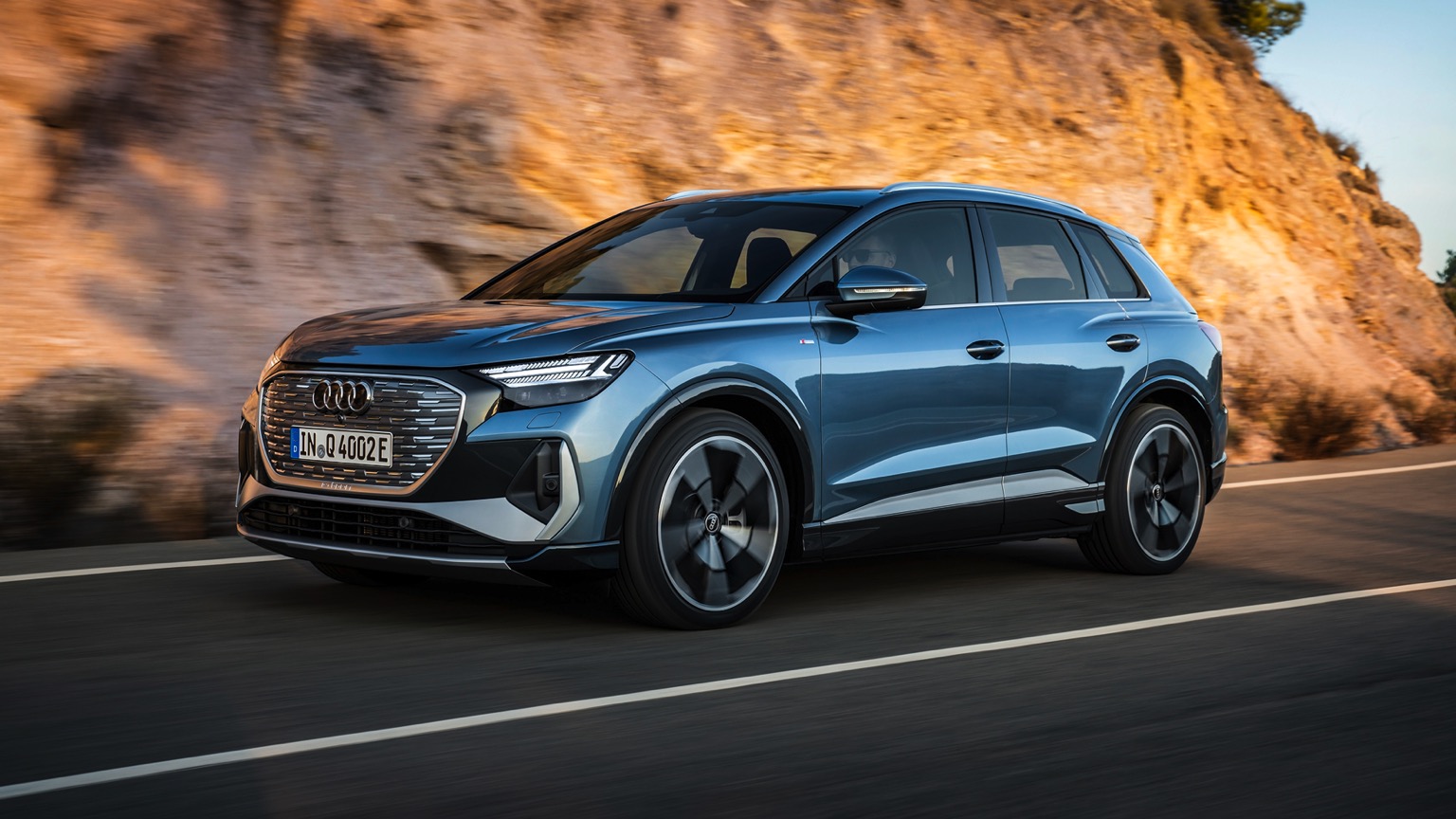 Elegantní stříbrné Audi Q4 e-tron parkující před moderním showroomem